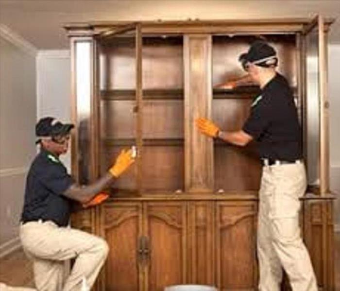 Two technicians cleaning a cabinet after a fire 